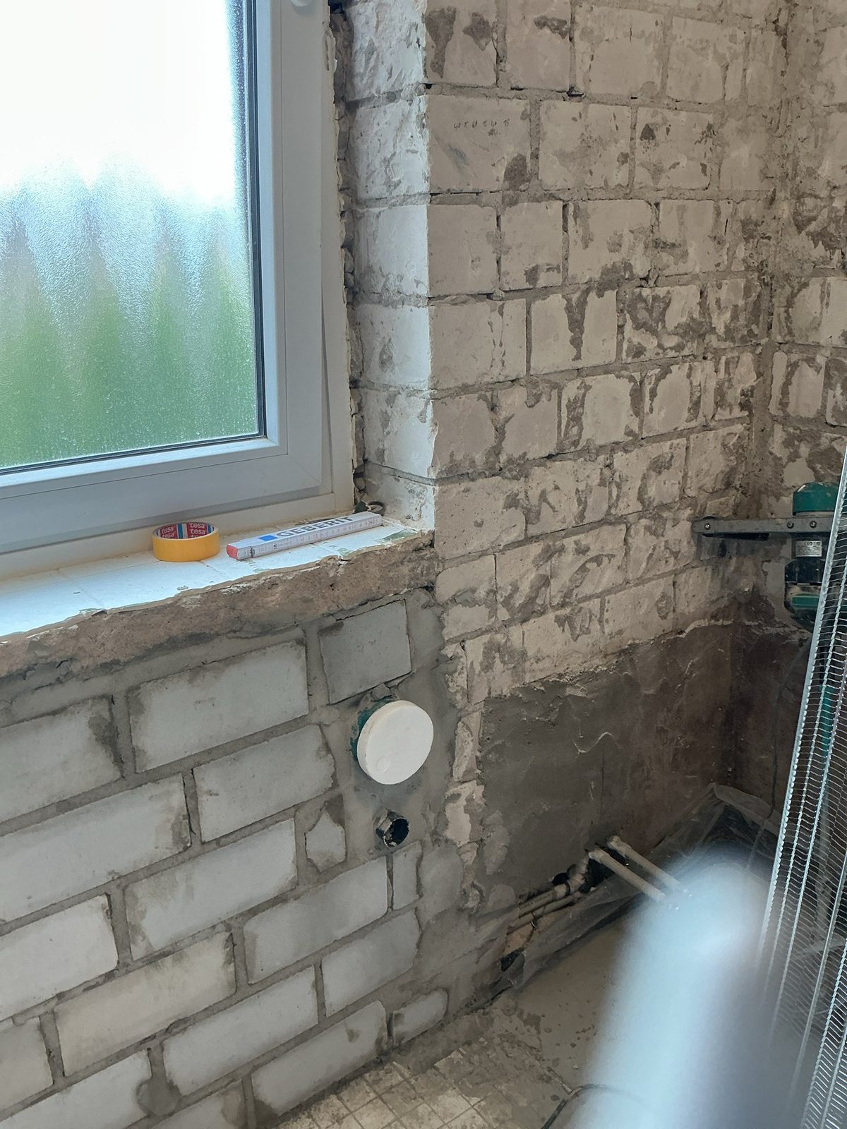 Zollstock auf der Fensterbank, darunter neu verlegter Ablauf